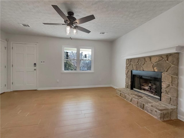 unfurnished living room with a stone fireplace, visible vents, wood finished floors, and baseboards