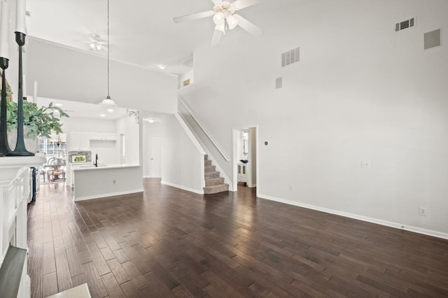 unfurnished living room with ceiling fan, dark hardwood / wood-style floors, and a towering ceiling