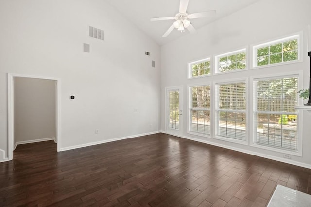 unfurnished room with ceiling fan, a towering ceiling, and dark wood-type flooring