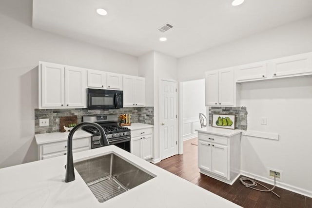 kitchen featuring gas stove, white cabinetry, and sink