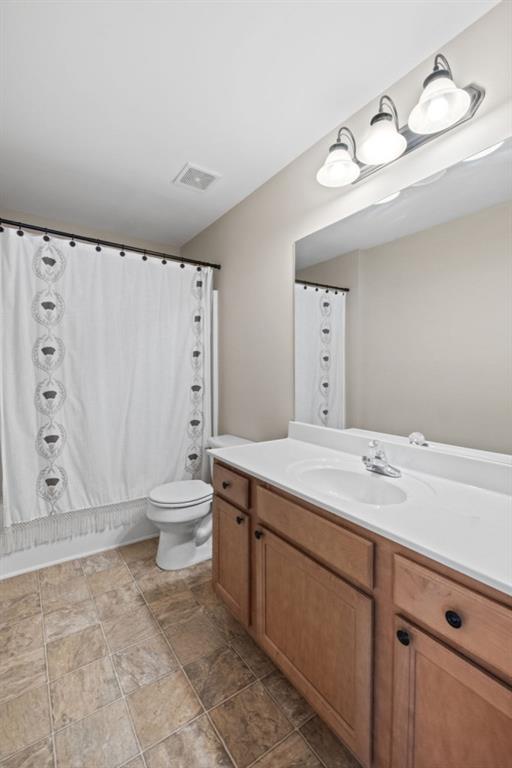 full bathroom with vanity, shower / tub combo, and toilet