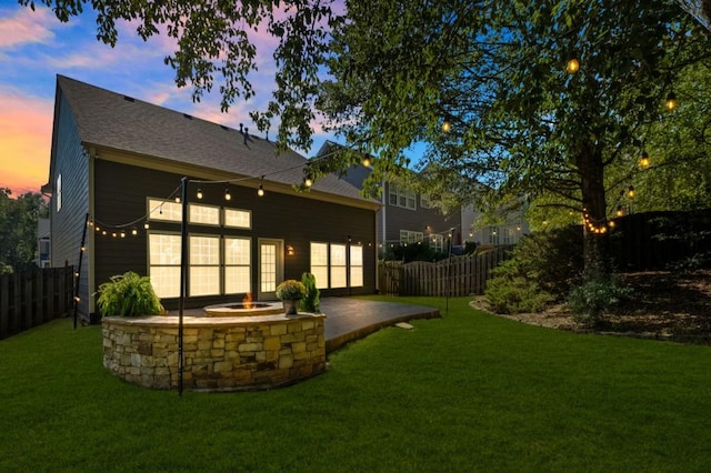 back house at dusk with a patio area and a yard