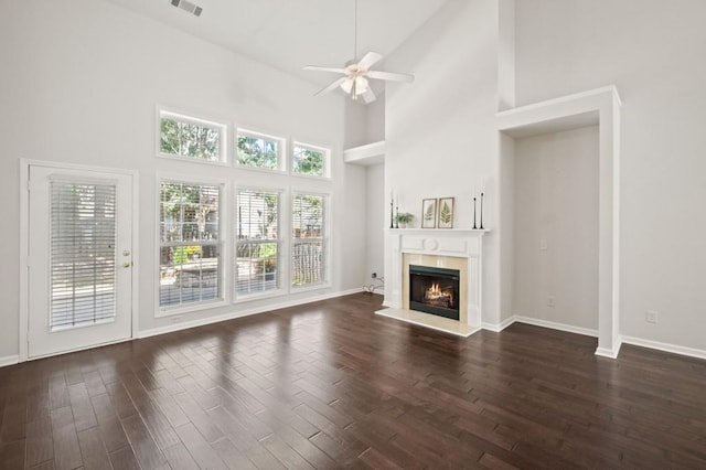 unfurnished living room featuring a towering ceiling, ceiling fan, and dark wood-type flooring