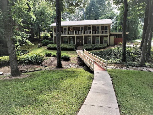 rear view of house with a lawn and a balcony