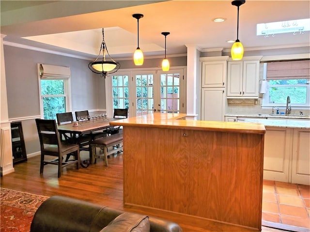 kitchen with pendant lighting, french doors, a raised ceiling, and sink