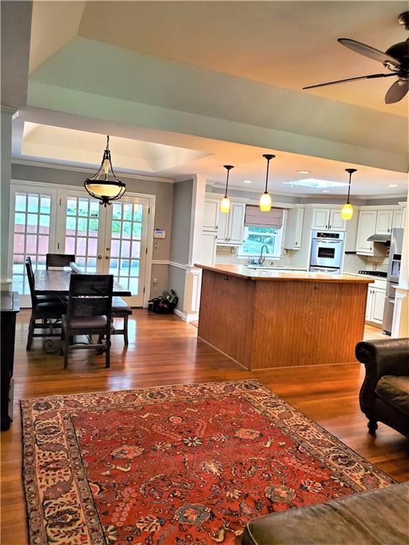 kitchen with ceiling fan, french doors, hardwood / wood-style floors, white cabinets, and a raised ceiling