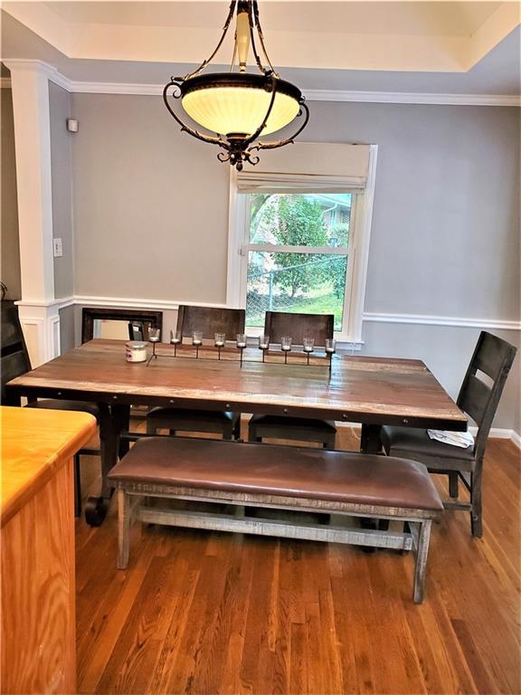 dining area featuring dark hardwood / wood-style flooring, a raised ceiling, and ornamental molding