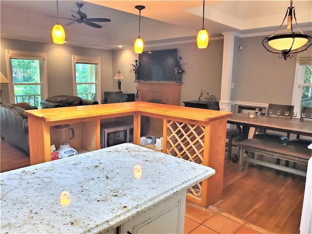 kitchen featuring ceiling fan, stainless steel microwave, white cabinets, light tile flooring, and light stone countertops