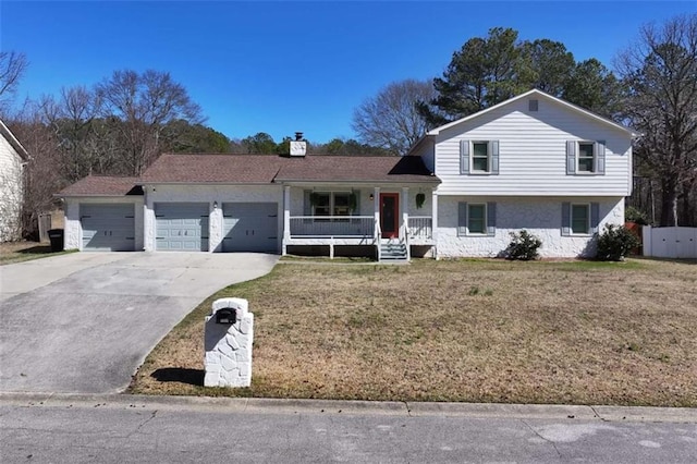 split level home with a garage, a front yard, covered porch, and driveway