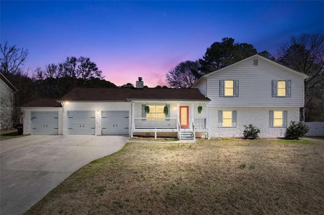 split level home with a chimney, stucco siding, concrete driveway, an attached garage, and a front lawn