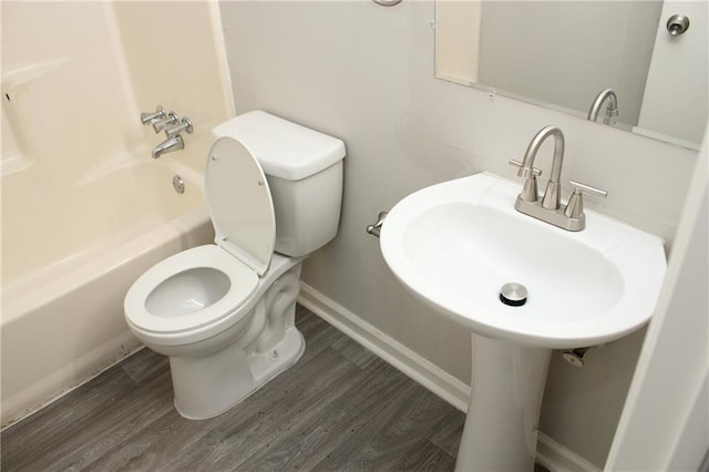 bathroom with toilet, bathing tub / shower combination, and hardwood / wood-style floors