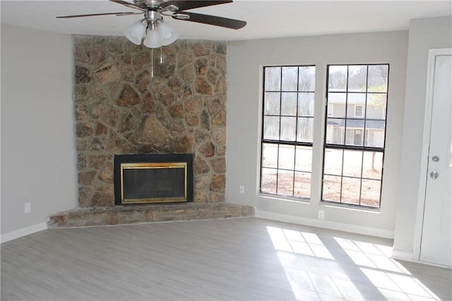 unfurnished living room with a fireplace, ceiling fan, and light wood-type flooring