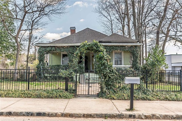 bungalow-style house featuring roof with shingles, a chimney, a gate, and a fenced front yard
