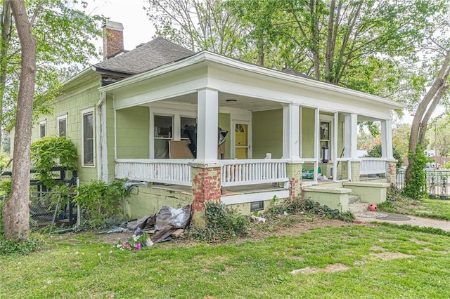 bungalow-style home featuring a front yard, fence, covered porch, and a chimney