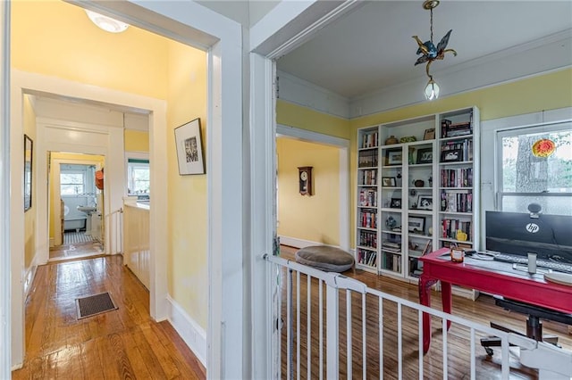 office space featuring crown molding, visible vents, baseboards, and hardwood / wood-style flooring