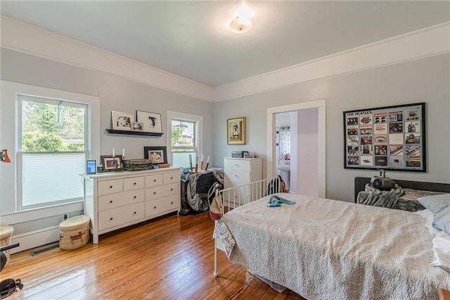 bedroom featuring crown molding, visible vents, multiple windows, and hardwood / wood-style flooring