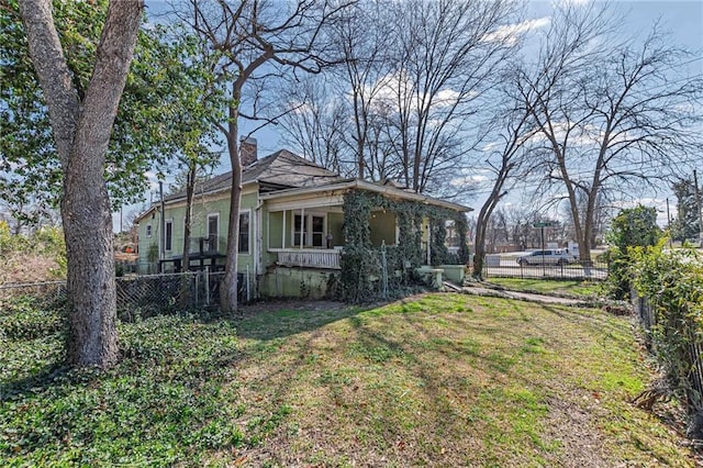 view of side of property featuring a yard, fence, and a chimney