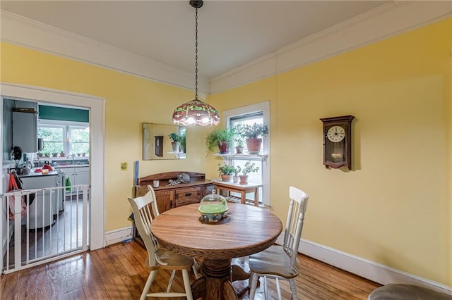 dining space featuring crown molding, wood-type flooring, and baseboards