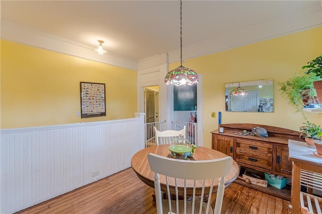 dining area featuring wood finished floors, ornamental molding, and wainscoting