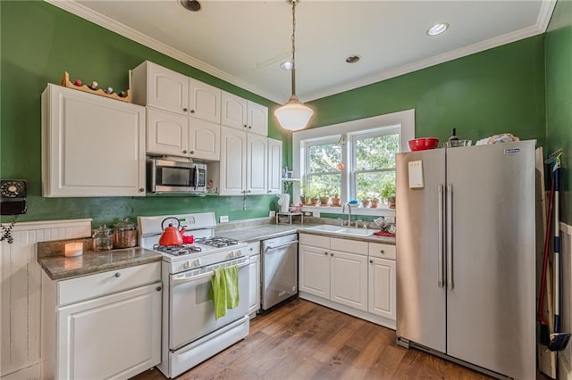 kitchen with ornamental molding, white cabinetry, appliances with stainless steel finishes, a sink, and hanging light fixtures