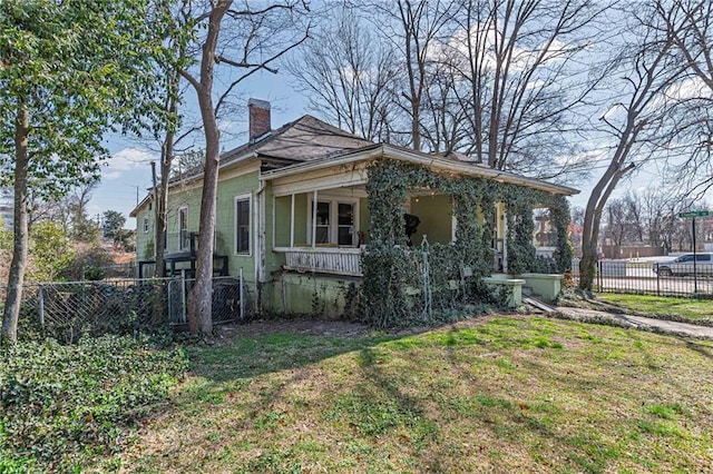 view of front of property with a porch, fence, a front lawn, and a chimney