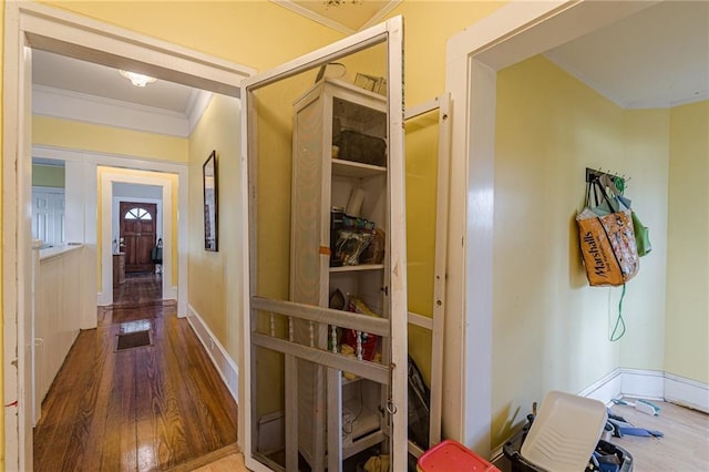 hall featuring baseboards, crown molding, and wood finished floors