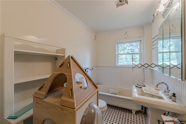 bathroom with a tub, ornamental molding, toilet, and wainscoting