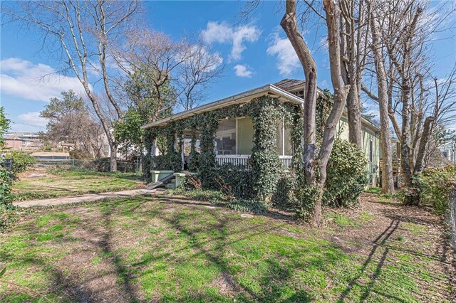 view of property exterior featuring a yard, a porch, and fence