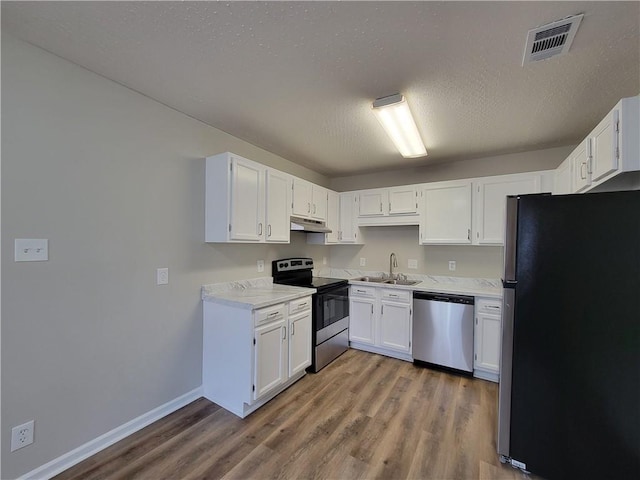 kitchen featuring hardwood / wood-style flooring, appliances with stainless steel finishes, sink, and white cabinets