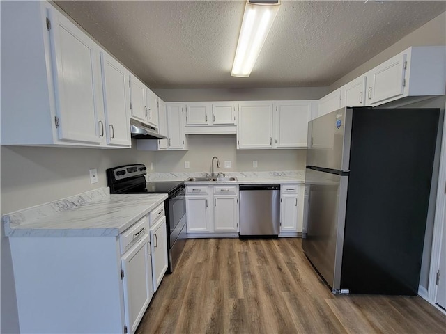 kitchen with stainless steel appliances, white cabinetry, sink, and hardwood / wood-style floors