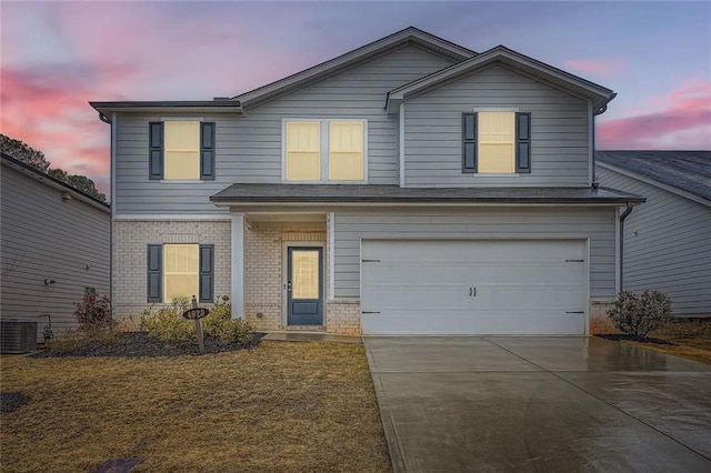 traditional-style home with driveway, an attached garage, brick siding, and central AC