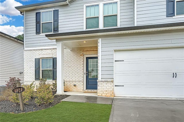 entrance to property with an attached garage and brick siding