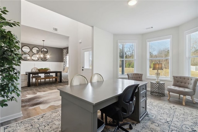 office with light wood-type flooring and an inviting chandelier