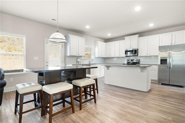 33 N Village Cir, Rydal, GA 30171 - kitchen with stainless steel appliances, a center island, light wood-style floors, a kitchen bar, and recessed lighting