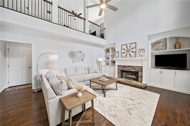 200 Glen Wood Pl, Canton, GA 30114 - living room featuring a ceiling fan, a high ceiling, a fireplace, dark wood-style flooring, and built in shelves