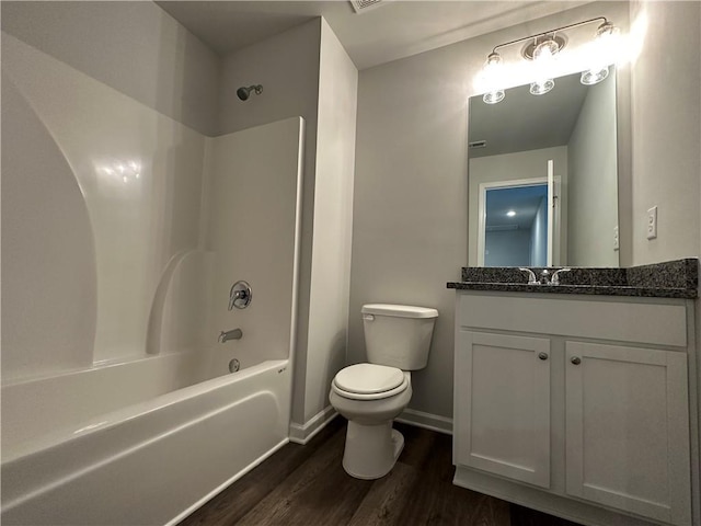 bathroom with toilet, wood finished floors, washtub / shower combination, vanity, and baseboards