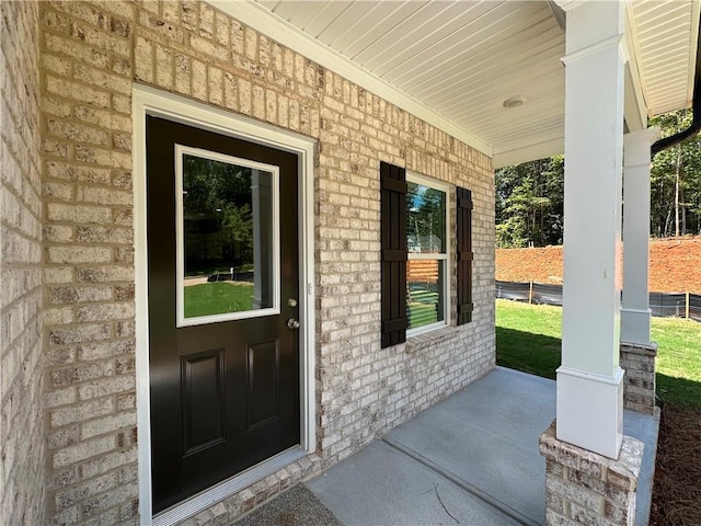 property entrance featuring covered porch and brick siding