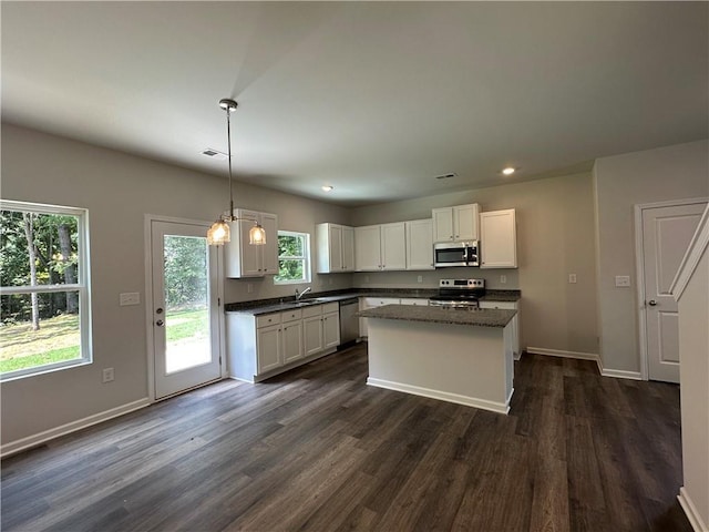 kitchen featuring stainless steel appliances, dark countertops, dark wood finished floors, white cabinetry, and baseboards