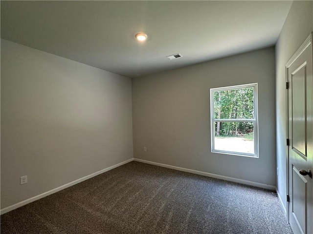 unfurnished room with dark colored carpet and baseboards