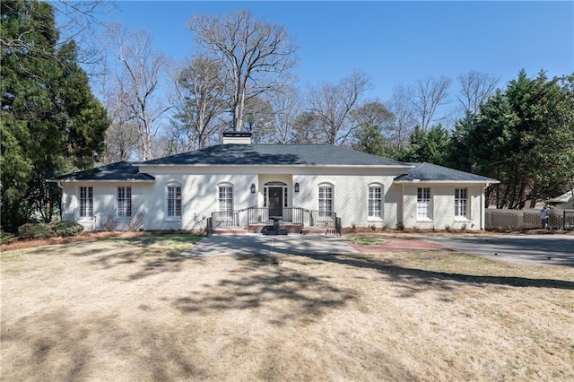 view of front of property with brick siding, a front lawn, a chimney, and fence