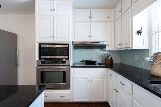 kitchen with under cabinet range hood, decorative backsplash, appliances with stainless steel finishes, and white cabinets