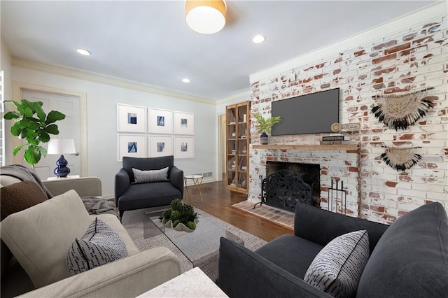 living room with crown molding, a brick fireplace, recessed lighting, and wood finished floors