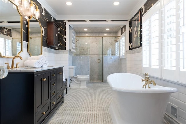 bathroom with tile walls, crown molding, a stall shower, a freestanding tub, and vanity