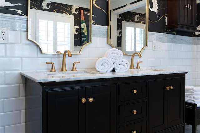 interior space with wallpapered walls, light stone counters, dark cabinets, and a sink