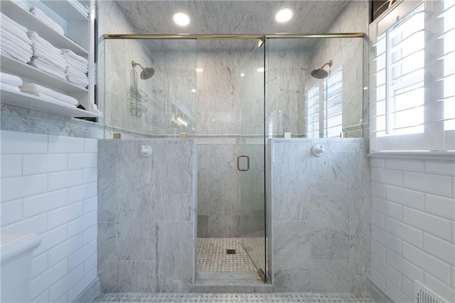 full bathroom featuring toilet, tile walls, and a stall shower