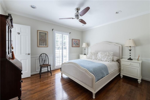 bedroom with dark wood finished floors, a wainscoted wall, ceiling fan, and ornamental molding