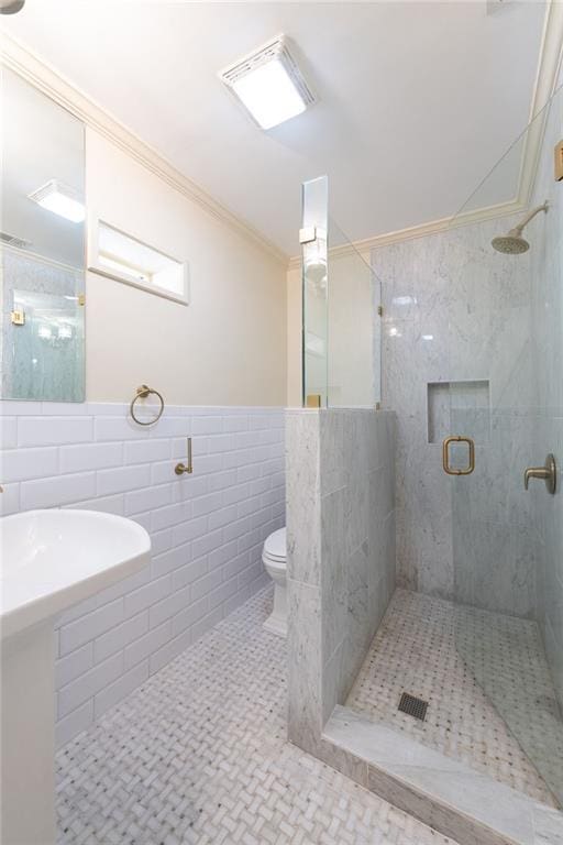 full bath featuring a stall shower, tile patterned flooring, crown molding, toilet, and tile walls