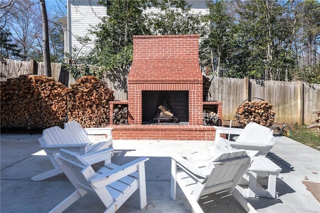 view of patio / terrace with fence and an outdoor brick fireplace