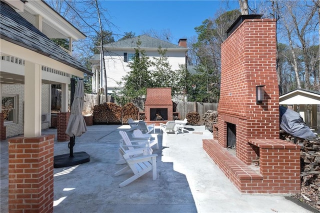 view of patio with fence and an outdoor brick fireplace