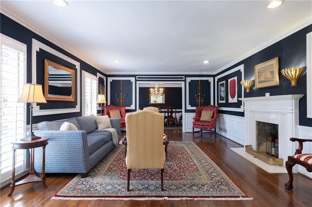 living area featuring a premium fireplace, wood finished floors, an inviting chandelier, and ornamental molding